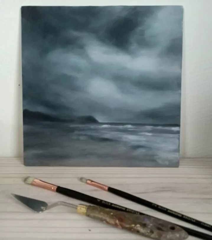 Misty landscape of a seashore with dark clouds and whitecapped waters. Dark tonal painting with hints of color. 