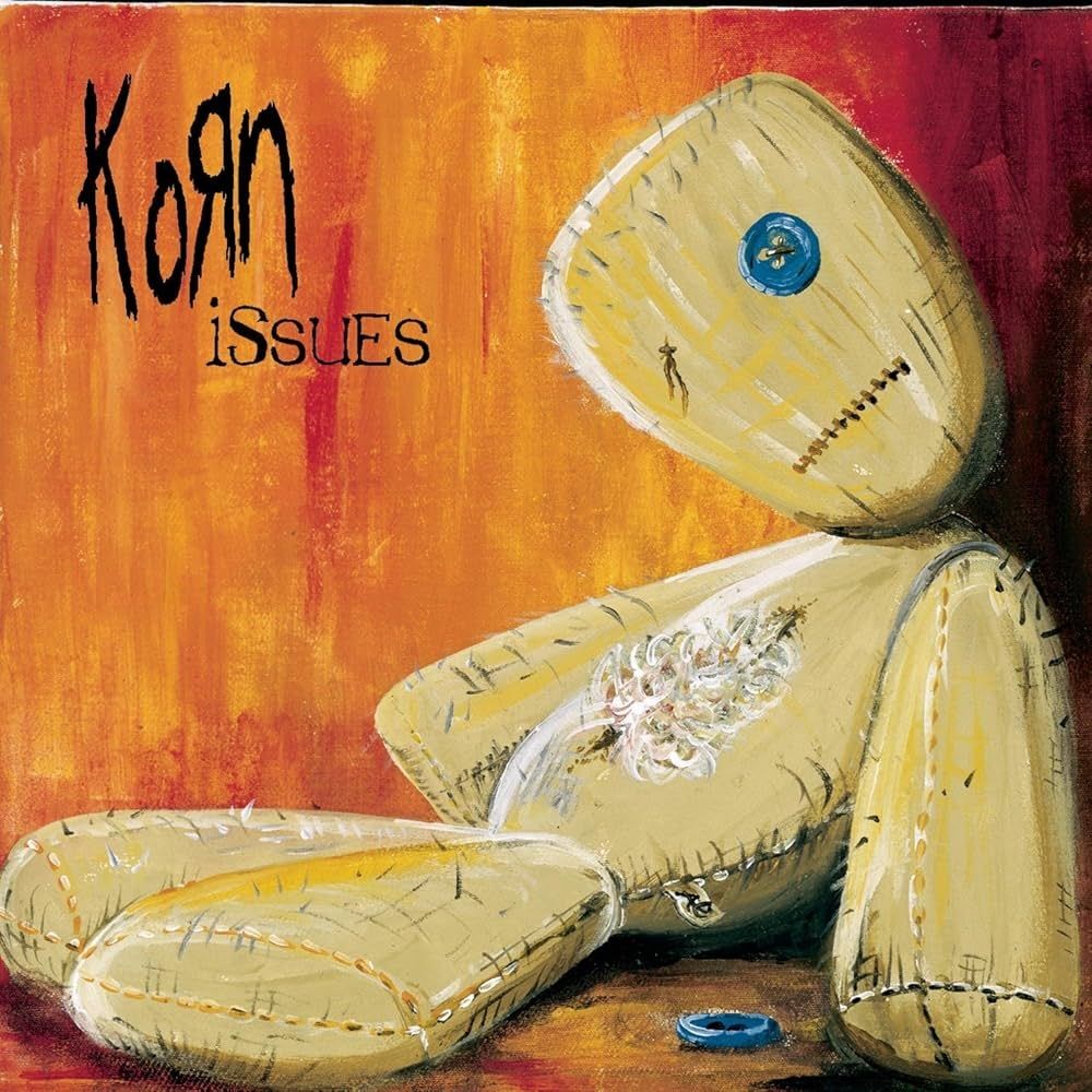 Korn - Issues Album Cover, welches eine Stoffpuppe zeigt, deren Bauch aufgeschlitzt ist und der ein Knopfauge fehlt.