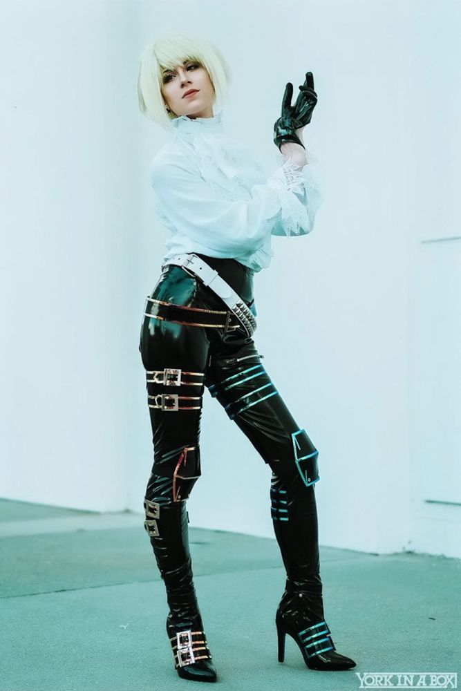 Steff cosplaying as Lio from Promare. Light neon green hair, white shirt, oil slick pants with a lot of buckles and straps 