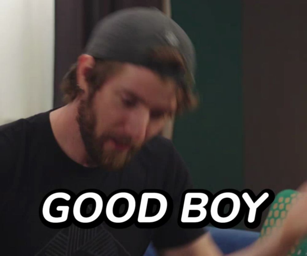 a man wearing a hat and a black shirt with the words good boy below him