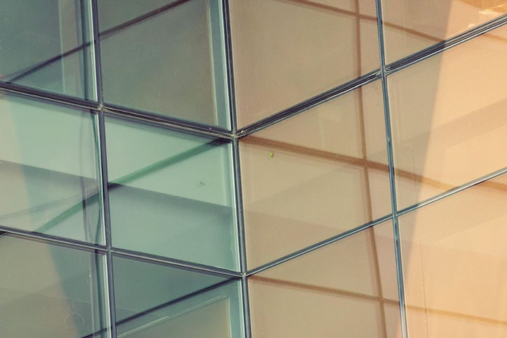 An glass wall from the left meets and orange wall at the right at a 90 degree angle creating an abstract pattern