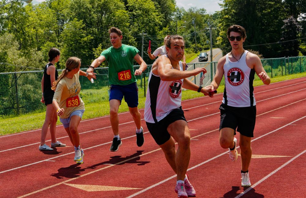 In two separate lanes two groups of runners simultaneously hand off their batons