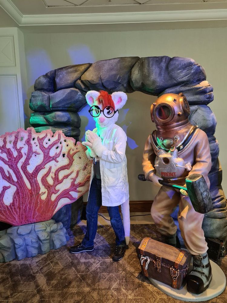 August the rat in a lab coat next to some underwater themed items