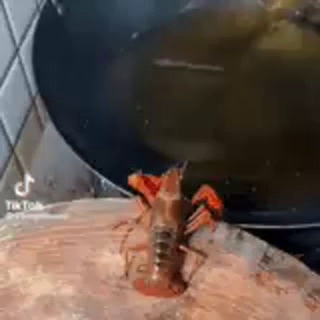 a lobster is sitting on top of a cutting board next to a pot of soup .