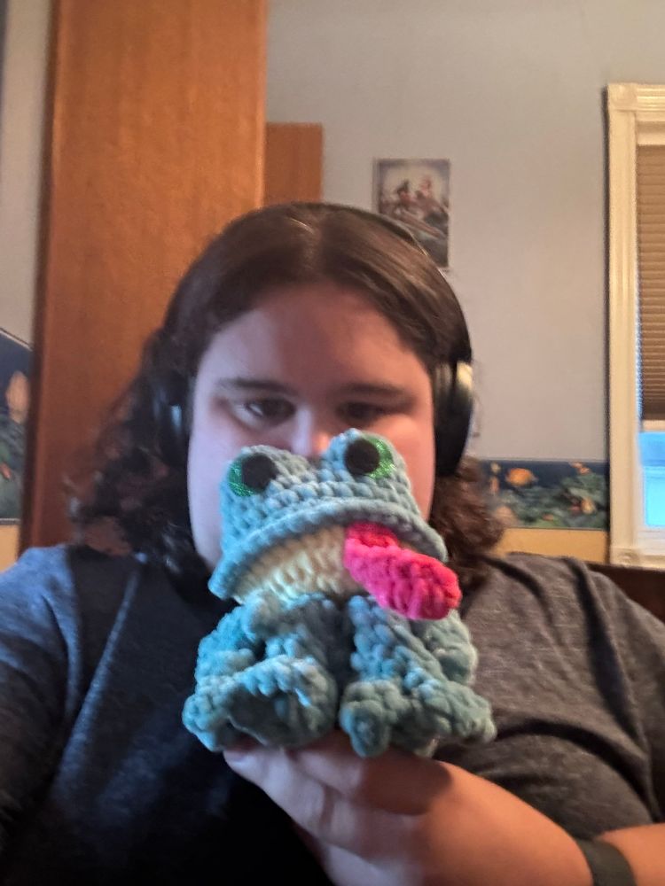 Sarah holding up her crocheted stuff frog
