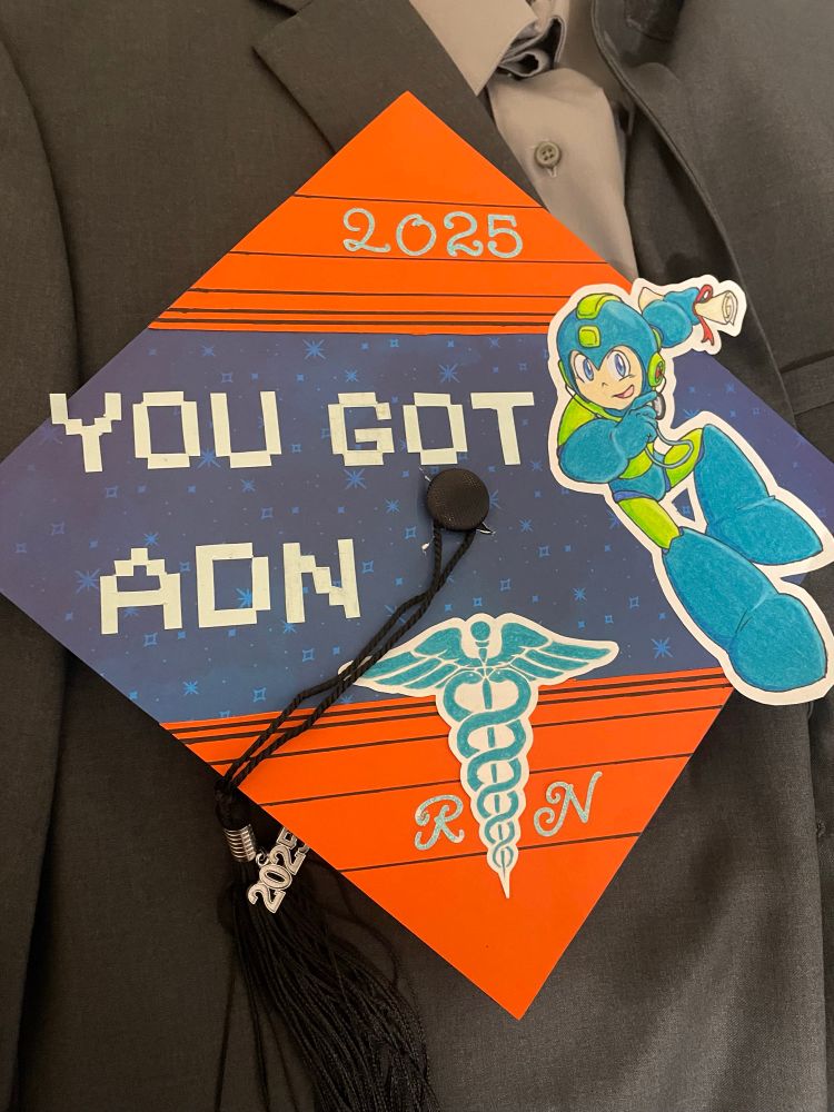 I decorated my graduation cap in the style of MegaMan 3 “Weapon Get.” MegaMan is holding a rolled up degree (left hand) and a stethoscope (right hand). His color scheme is college’s colors.