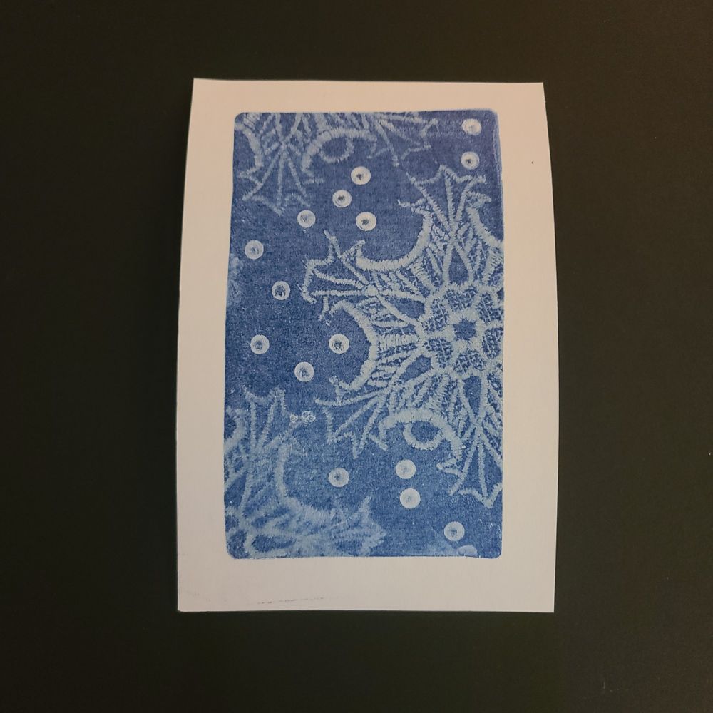Gelli plate print of embroidered snowflake with navy acrylic paint 