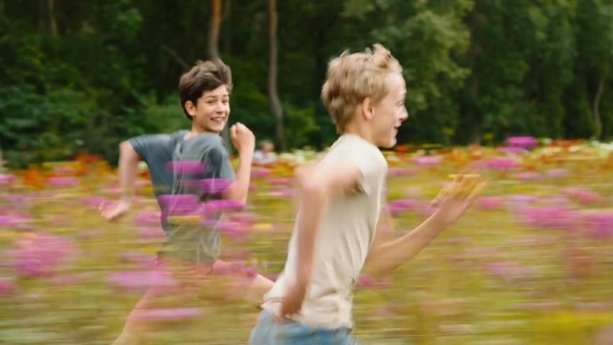 Screenshot from the movie Close where two boys are running through the flowers' plantations.
