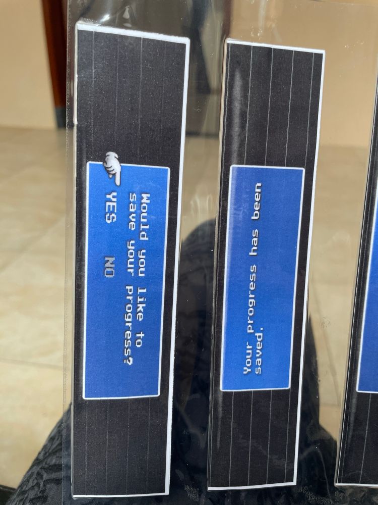 Two laminated bookmarks. One side says, “Would you like to save your progress? Yes No” and the other side says “Your progress has been saved.”