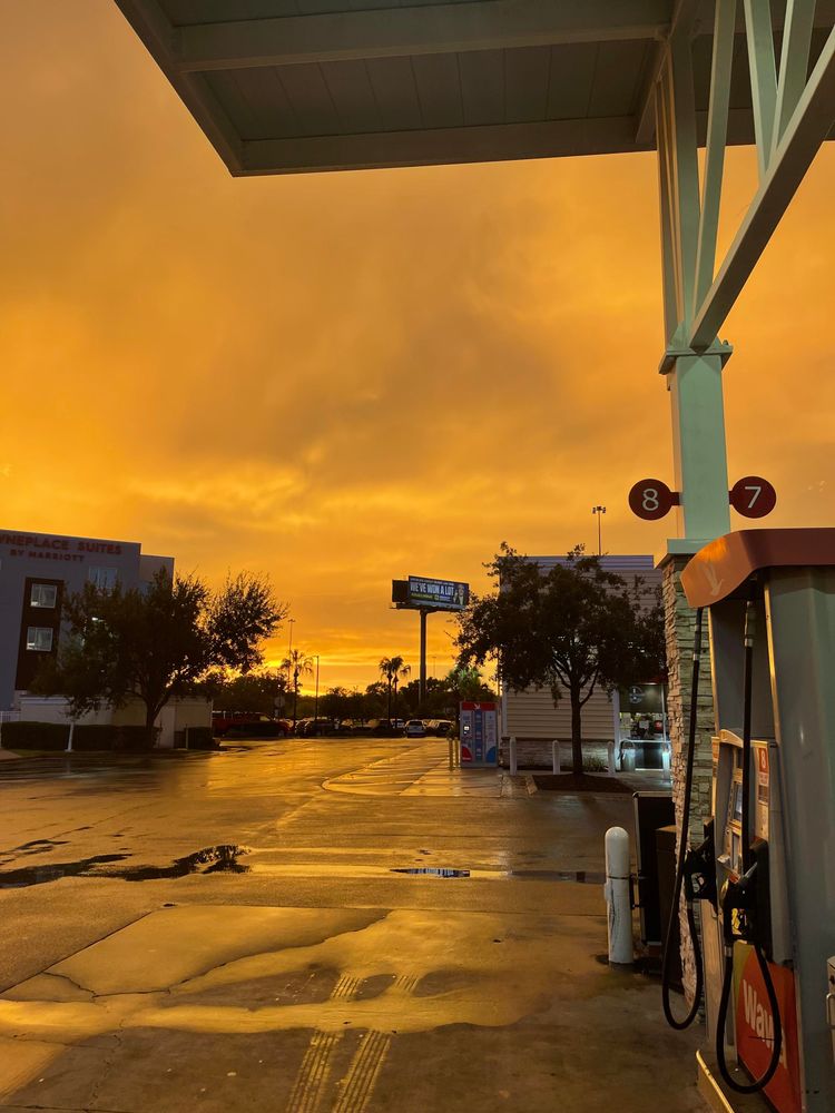 Sunset behind a gas station, with some reflections on a wet road surface
