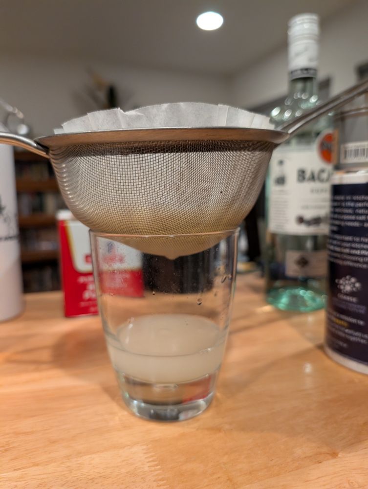 A coffee filter lined sieve filled with curdled milk, citrus, simple syrup, and booze slowly dripping into a glass.

It will obviously need multiple filtrations.