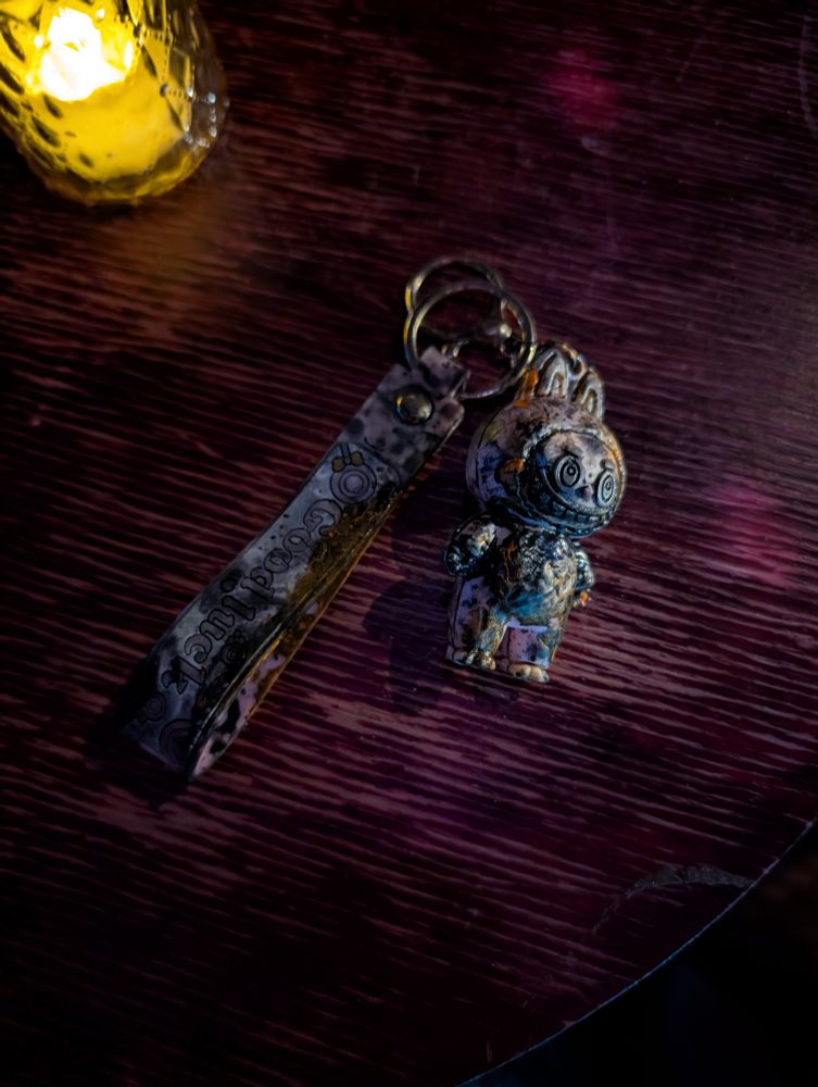 A distressed labubu keychain sitting on a dark wood table.