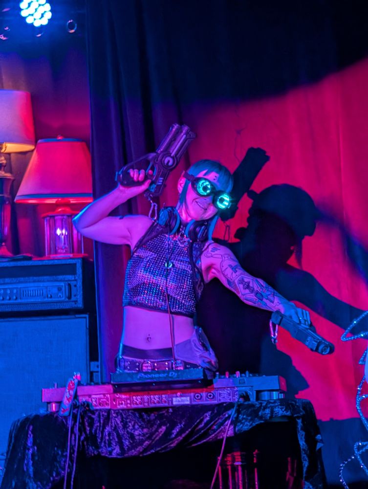 K1K1 posing with her prop futuristic energy pistols. Red and blue light mixes together for top notch bisexual lighting.
