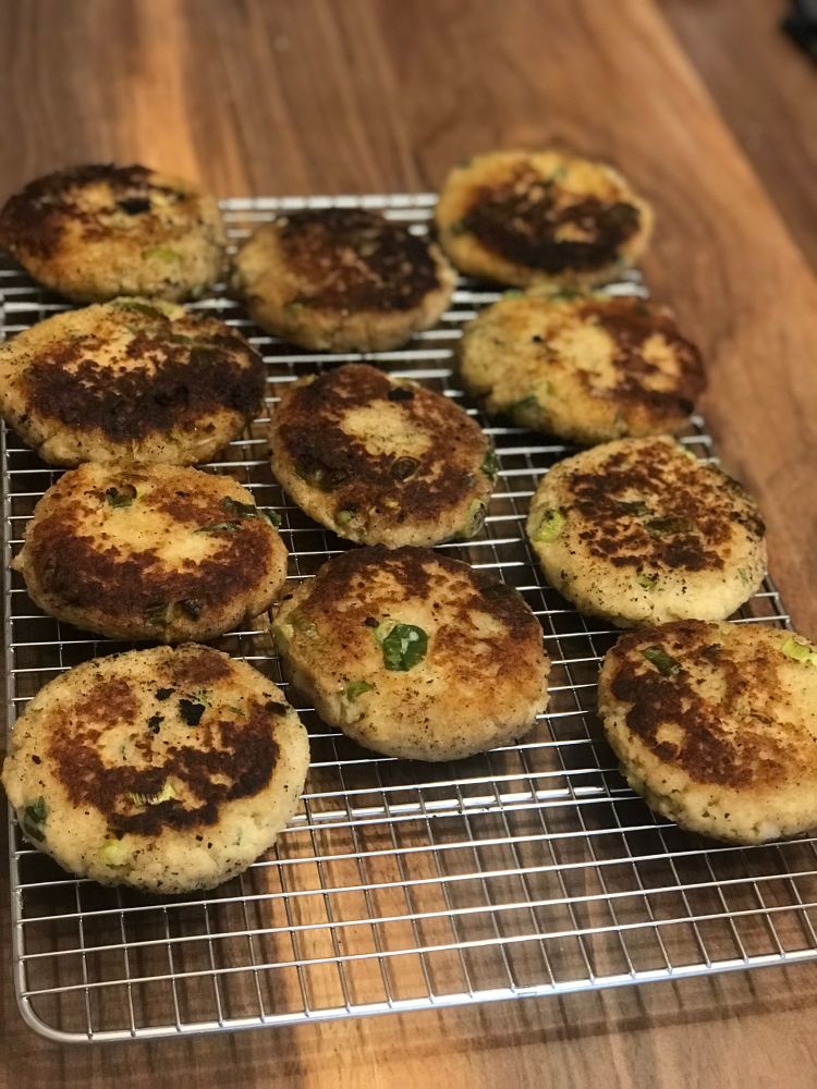11 round, fried cauliflower fritters cooling on a rack