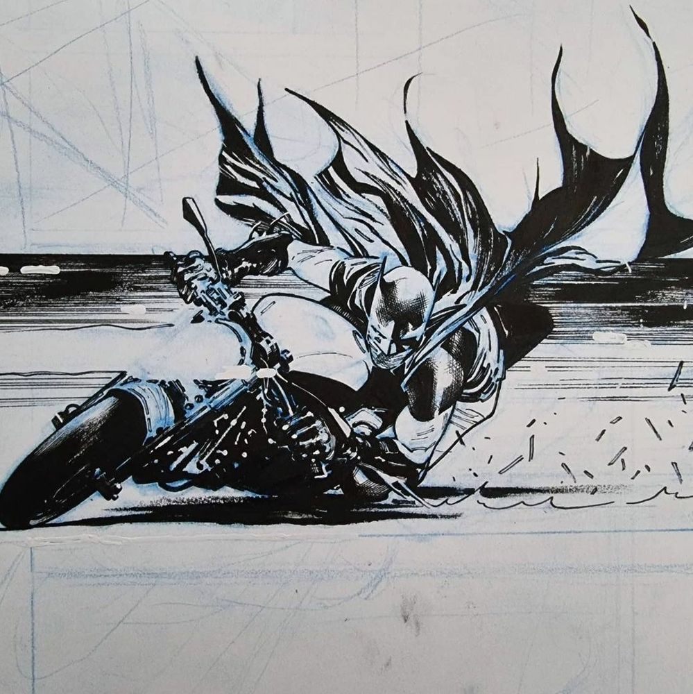 Closeup on Batman sliding on motorcycle on a comic art board. 