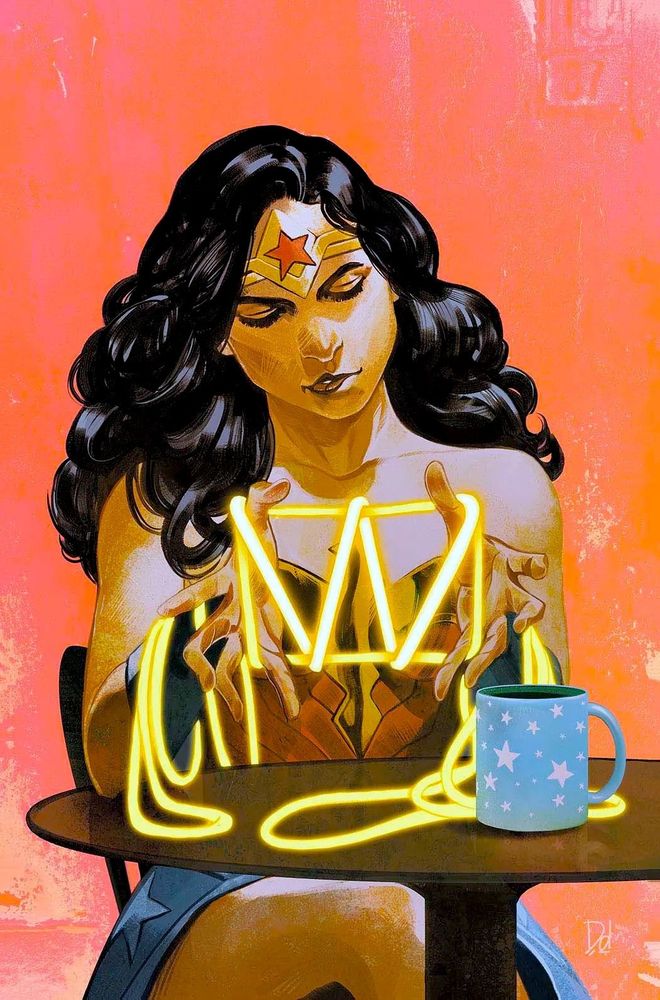 Wonder Woman sits at a small cafe style table for one to two. You see her on the other side of the table almost like you're sitting across from her. From bottom going up, you can see a little bit of her right leg crossed over her left behind the table pole, and some of the sides of her skirt. On top of small brown circular table you see a soft blue coffee mug with white stars on it. You see some of WW's lasso on the table and her elbows are on table as her hands hold the lasso in her fingers making a W. You see the top of her costume and her shoulders. Her head is slightly tilted to the right as she looks down at what she's making with her hands.