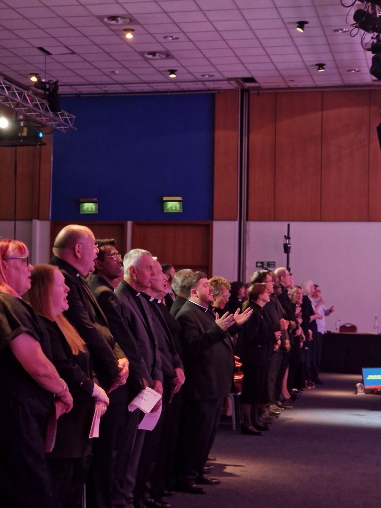 Photo if the Ordinands stood in rows singing in worship, all wearing black clothes.