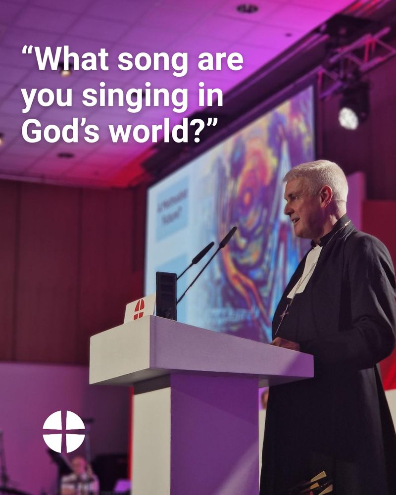Revd Richard Andrew speaking at the lectern at the Methodist Conference. Text reads 'what song are you singing in God's world?'. Methodist orb logo in the lower left corner. 