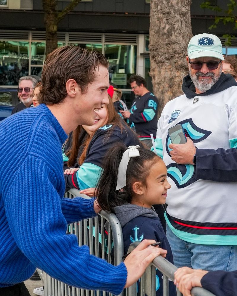Photo of Cale taking pictures with a young fan on the blue carpet on Opening Night.