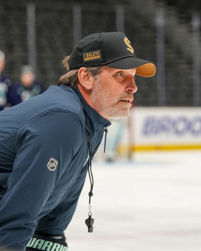a photo of Seattle Kraken head coach Lane Lambert wearing a Seattle Kraken Military Appreciation Night hat while his whistle hangs from his neck.