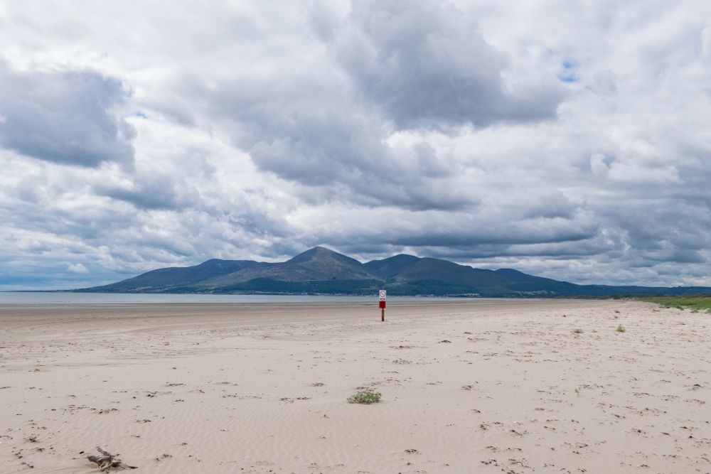 View across a deserted beach to the Mourne Mountains