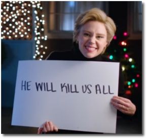 Kate McKinnon as Hillary Clinton holding up a sign that says he will kill us all 