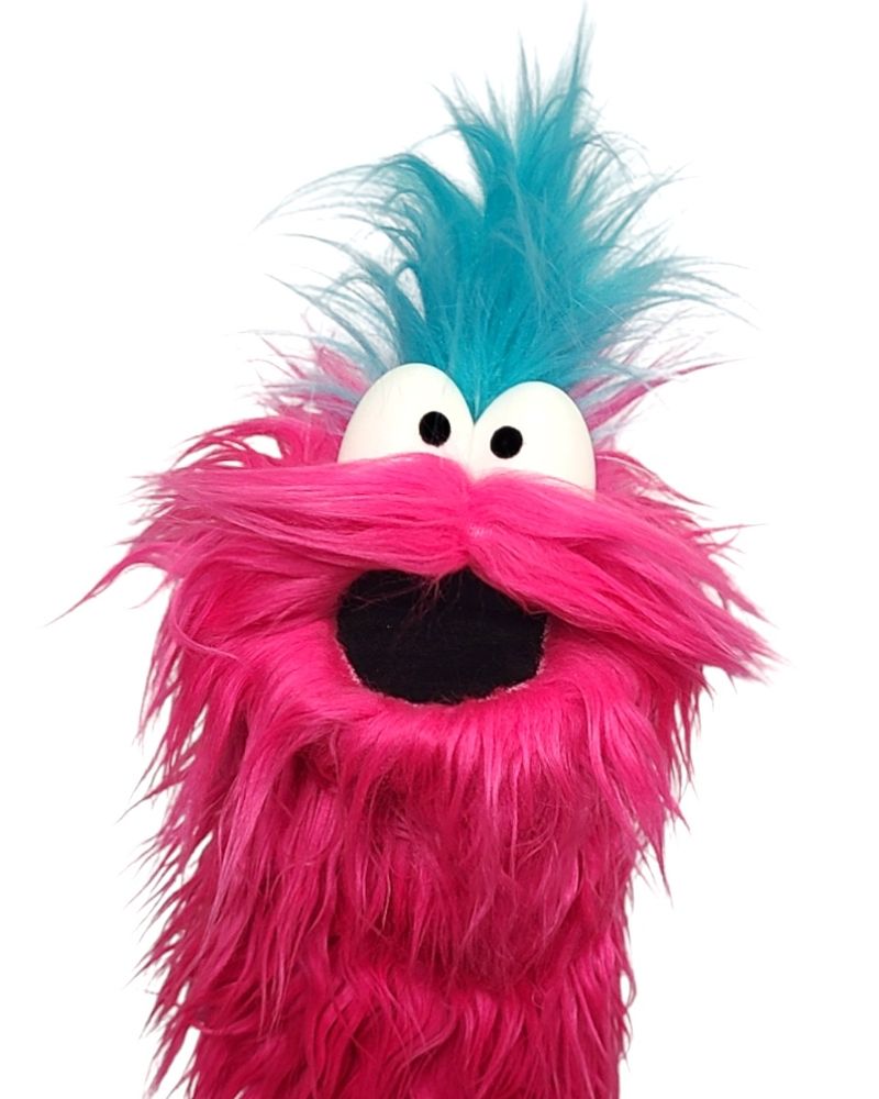 A little pink monster puppet that looks rather like a mustached pineapple with a blue tuft of hair