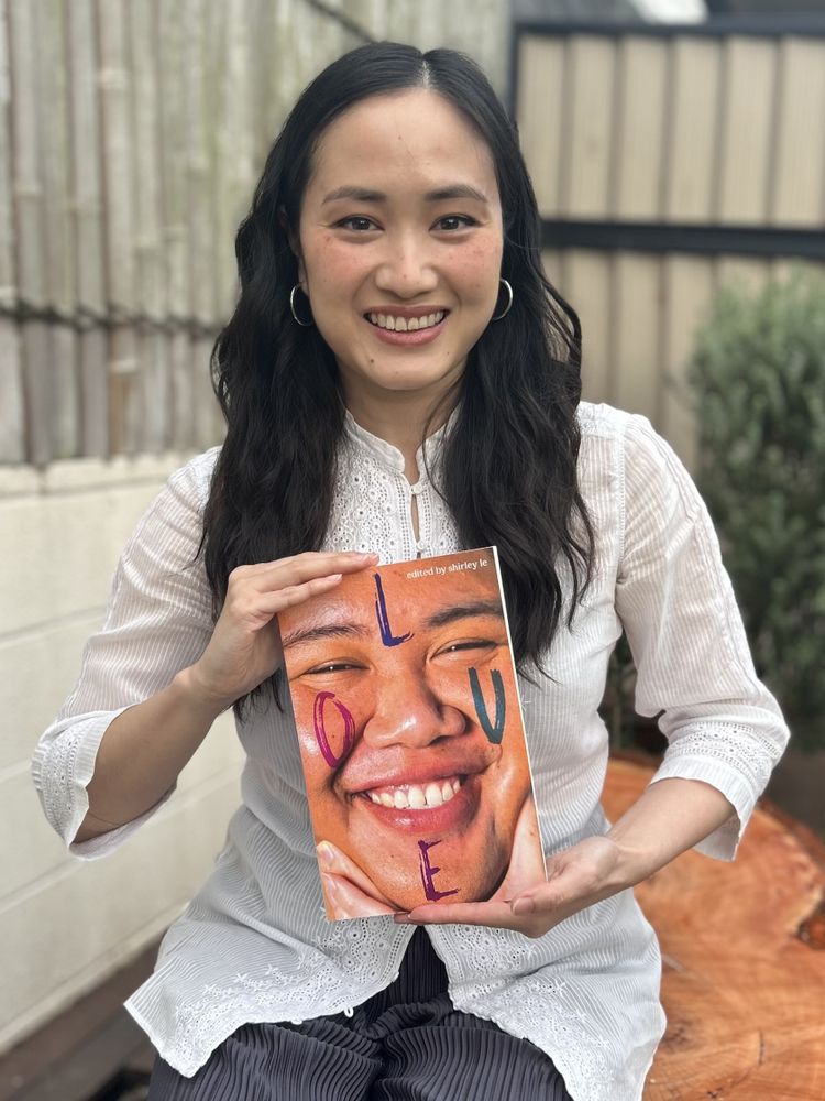 Editor Shirley Le holding a copy of Love outdoors