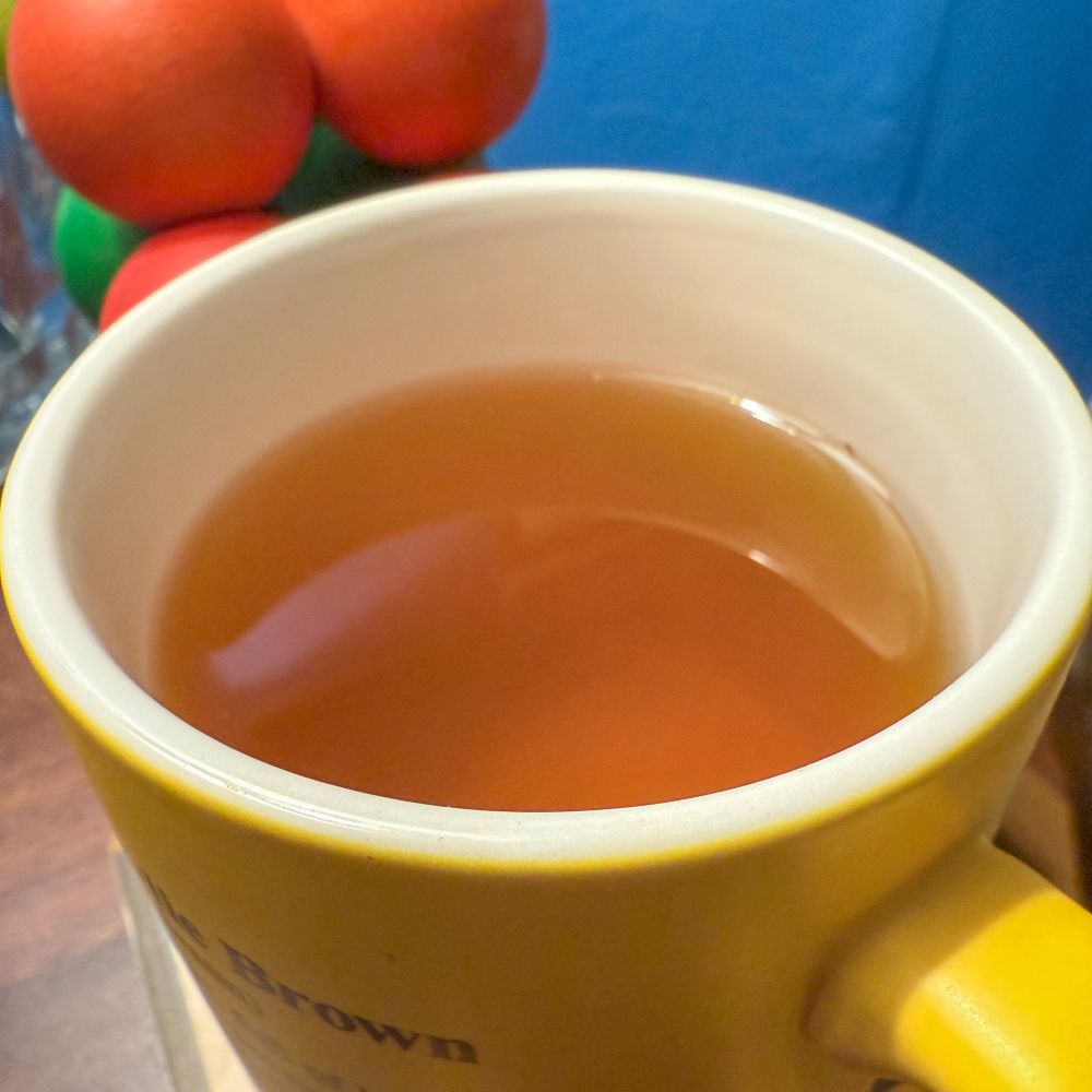 A closeup of a yellow mug steeped with green tea.