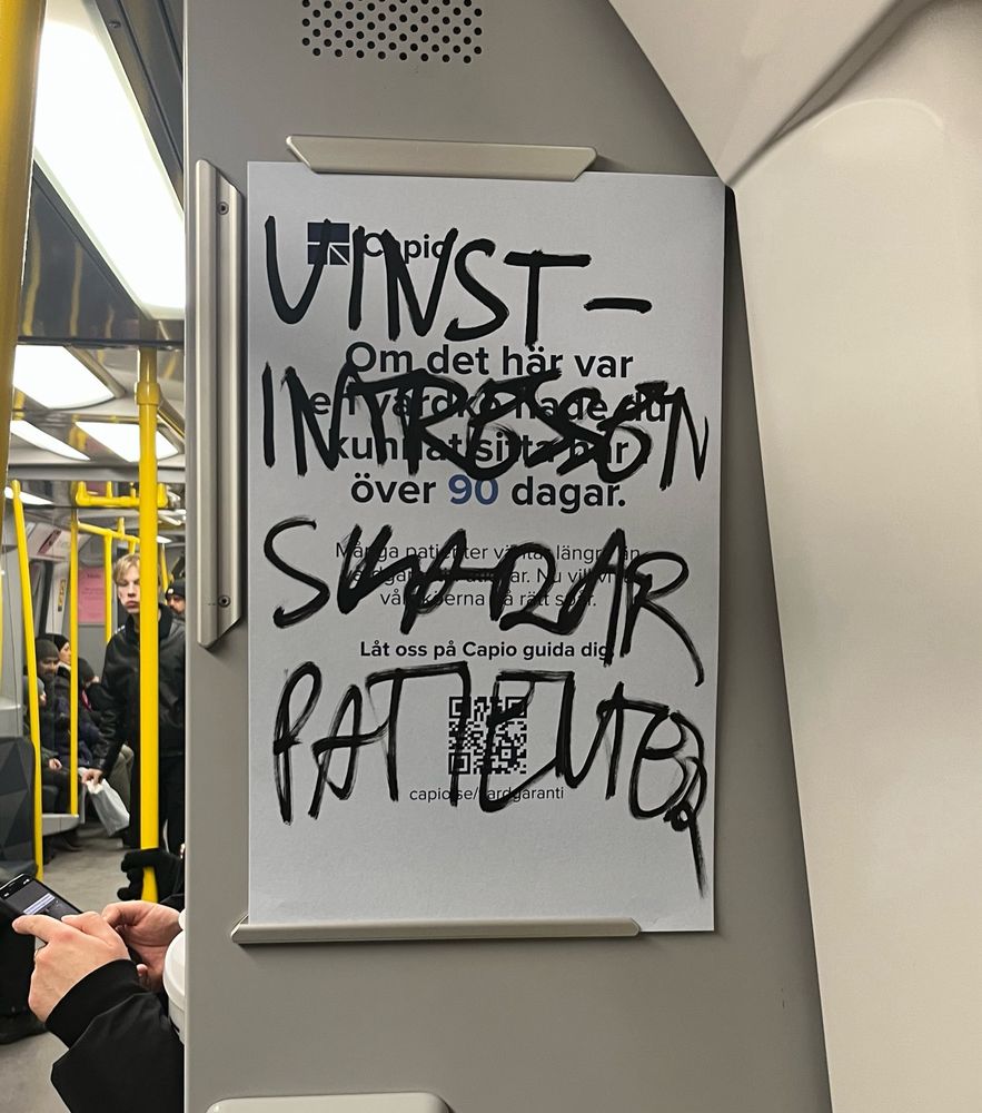 Skylt på tunnelbanan med reklam för privat vårdgivare. Klotter på skylten säger ”vinstintressen skadar patienter”