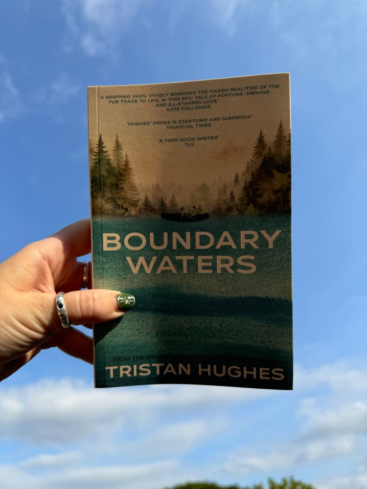 A copy of Tristan Hughes’ latest novel Boundary Waters up in the blue sky. 