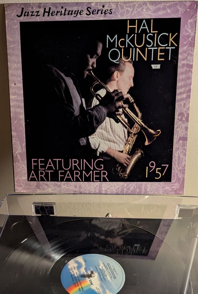 LP cover - standard Jazz Heritage Series template, with a mauve patterned border this time; in the center is a black and white photo of a Black man (Farmer) and a white man ( McKusick) from the side, illuminated with stage lighting. Farmer is blowing, McKusick is waiting his turn on alto. Farmer is wearing a dark shirt that looks like flannel; McKusick is wearing a white dress shirt with vertical stripes, alternating thick and thin.