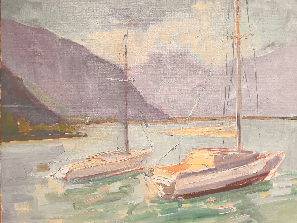Two boats in morning light on large Alpine lake with misty mountains backdrop