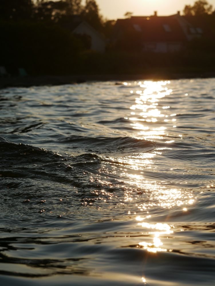 peaaegu sile vesi, jookseb krobeliselt üle pinna aluse kivi, päike peegeldab mööda veepinda
