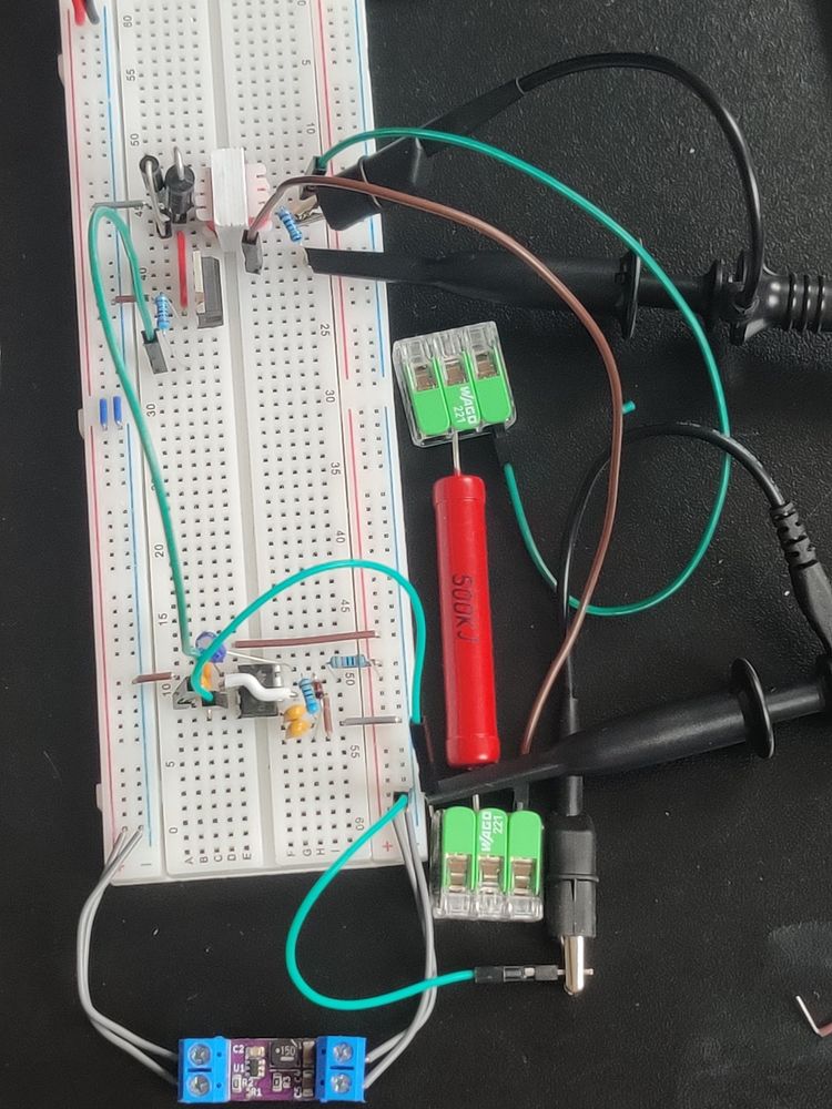 My breadboard setup with my 5V buck below hooked up to a 555 timer that is driving a chunky transistor at the top connected to a transformer and flyback diode + (30V Zener in series with that)