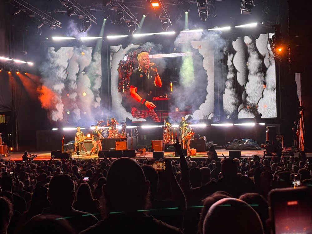 The Offspring n stage playing at White River Amphitheater in Auburn, WA. On the video screen behind the band, Dexter Holland sings. 
