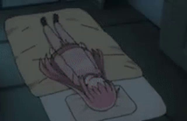 a girl with pink hair is laying on her back on a bed in a dark room .