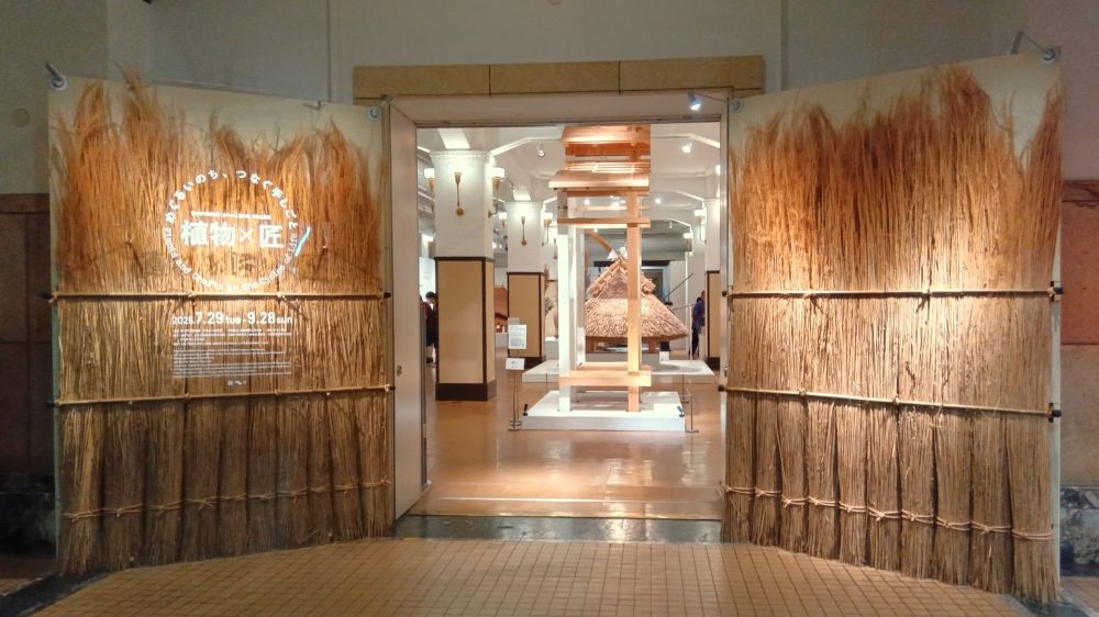 展示会場入口の大看板
干した茅の束が柵状に並べられたデザイン

「植物×匠
　めぐるいのち、つなぐ手しごと
　Plants and Crafts in the Cycles of Life
　2025.7.29 tue - 9.28 sun」