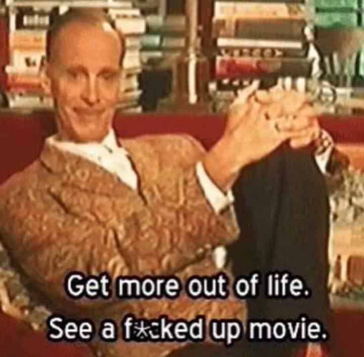 A meme of John Waters sitting back with hands folded over their left knee and text reading “get more of of life. See a f*cked up movie.” 