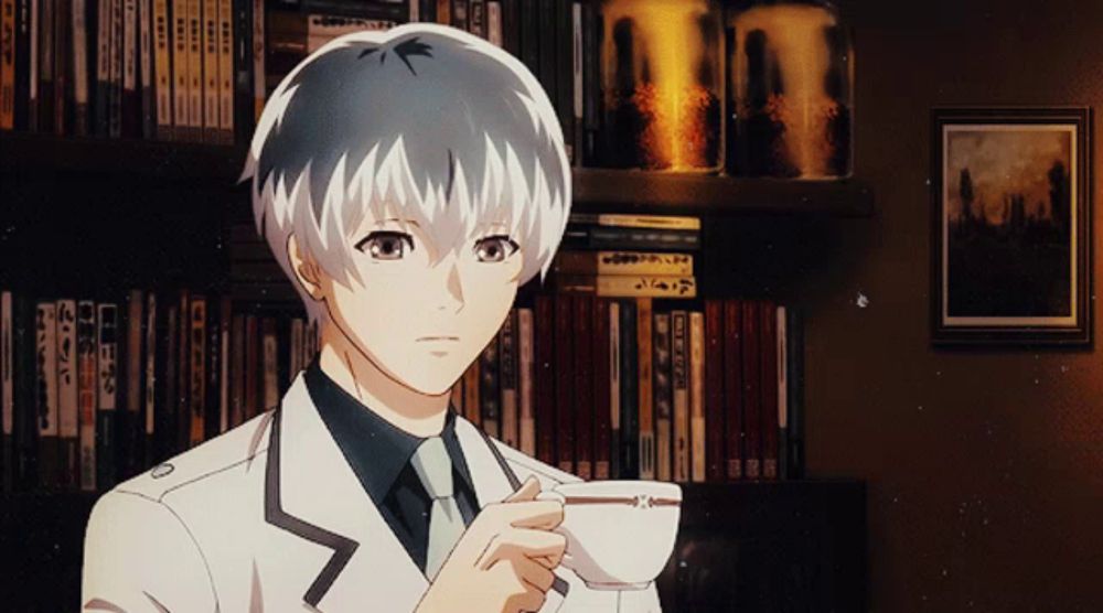 a man in a suit holds a cup of coffee in front of a shelf of books