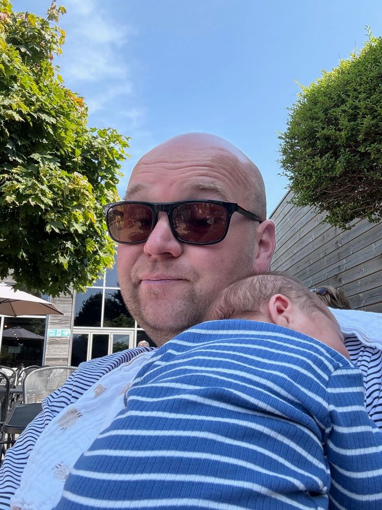 2 dudes in stripy tops, one 45 years old bald, wearing sunglasses, the other 3 weeks old, asleep  