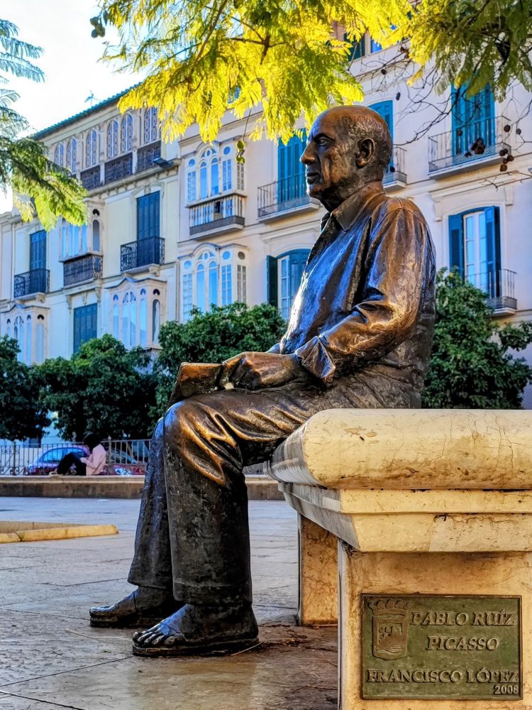 Skulptur von Francisco López:
Wir sehen Picasso, vor seinem Elternhaus, auf einer Bank im Schatten, unter Bäumen, in Malaga.
