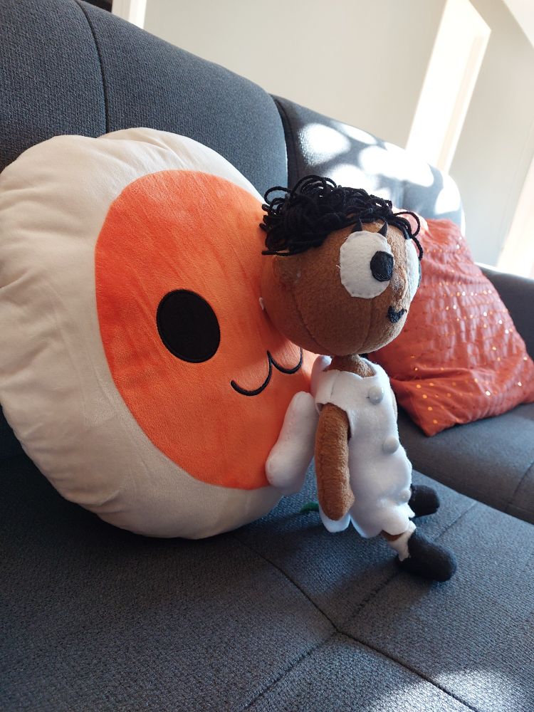  a Black Angel with a white dress and black shoes laying on a Taiko plush cushion 