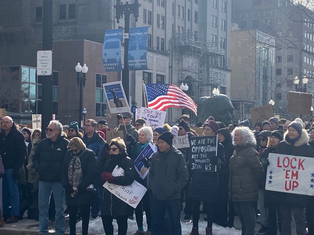 Outdoor Crowd in winter clothing holding American flags and Anti-tr*mp and anti- M*sk signs listen to speakers. 