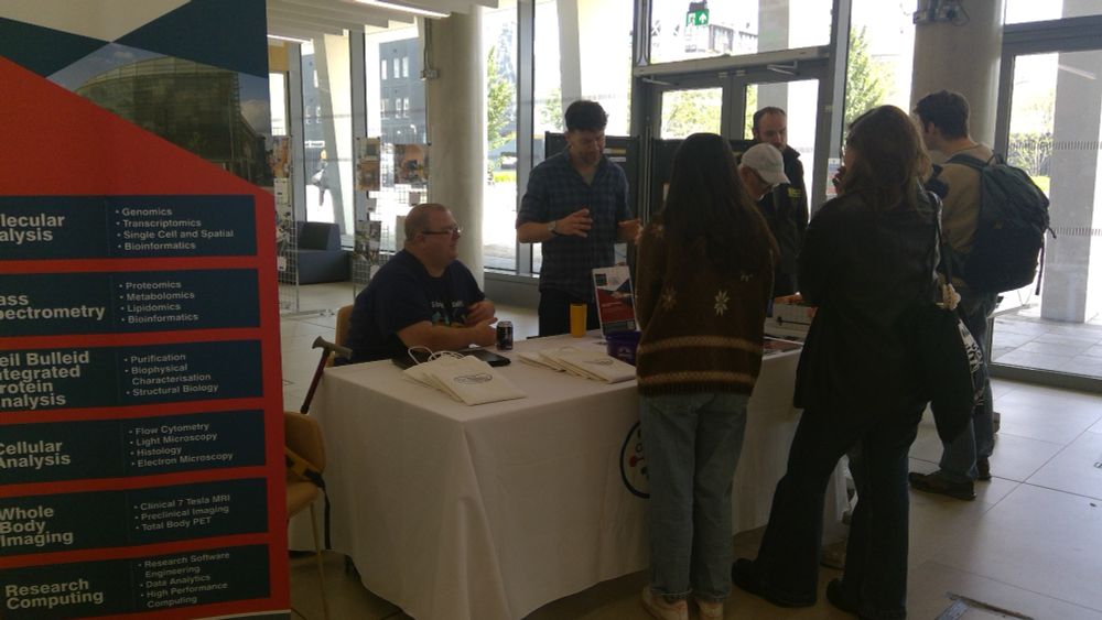 Photograph of people having a conversation about brilliant science at an exhibition table.