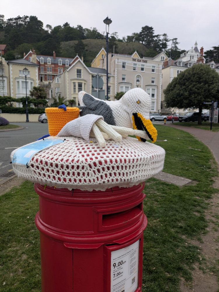 A crocheted seagull eating a crocheted fry atop a metal canister with a view of the fry packet 