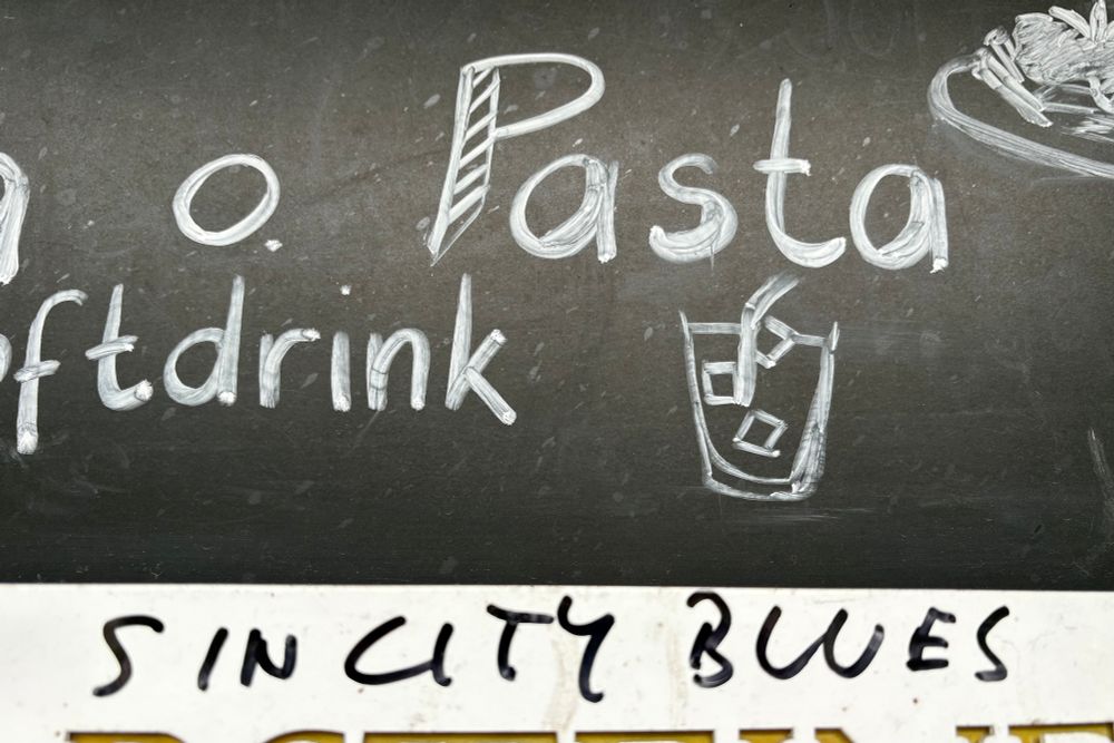 A sign at the restaurant where someone has scribbled “sin city blues.”