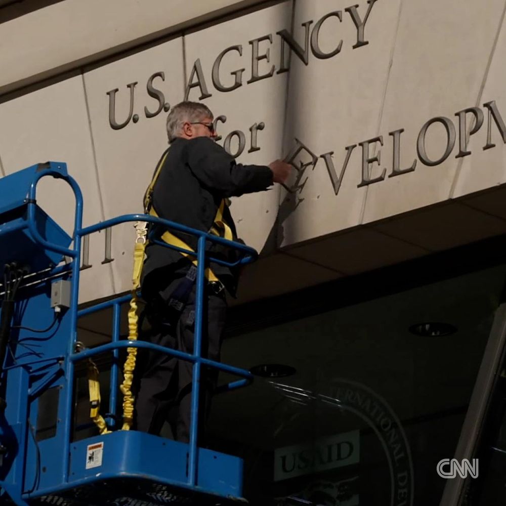 A worker removes the signage outside of the USAID headquarters in Washington, DC, on Friday.