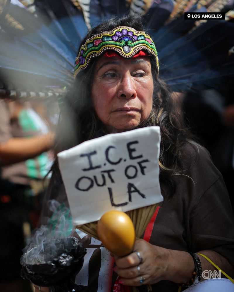 A demonstrator wearing indigenous attire with a sign reading "I.C.E. OUT OF LA" takes part in the "No Kings" protest in Los Angeles. | Daniel Cole/Reuters