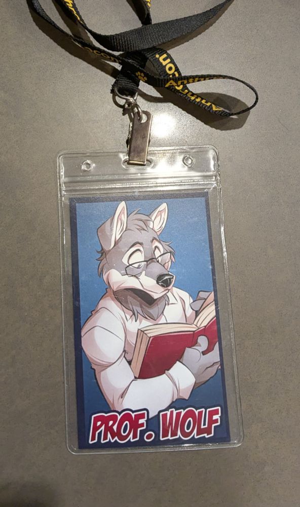Lanyard with my fursona, professor wolf (an anthro gray wolf) reading a book. He looks very innocent. 